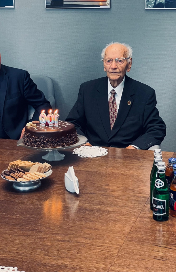 Jubilat pozuje do zdjęcia siedząc przy stole. 