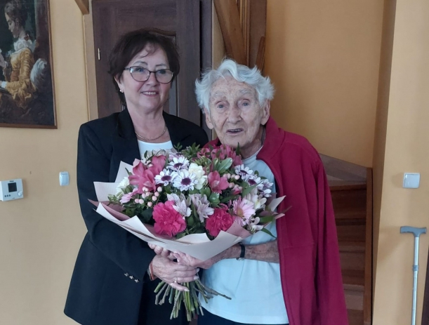 Przewodnicząca Sejmiku Województwa Zachodniopomorskiego Teresa Kalina pozuje do zdjęcia z panią Amelią Korycką, kombatantką, uczestniczką Powstania Warszawskiego. Wspólnie trzymają duży bukiet kwiatów. Wizyta odbyła się z okazji 97 urodzin pani Amelii.