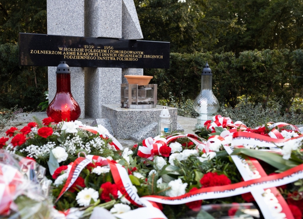 Wiązanki kwiatów i wieńce z biało-czerwonymi wstęgami ułożone przy pomniku z napisem "1939-1956 W HOŁDZIE POLEGŁYM I POMORDOWANYM ŻOŁNIERZOM ARMII KRAJOWEJ I INNYCH ORGANIZACJI ZBROJNYCH PODZIEMNEGO PAŃSTWA POLSKIEGO".