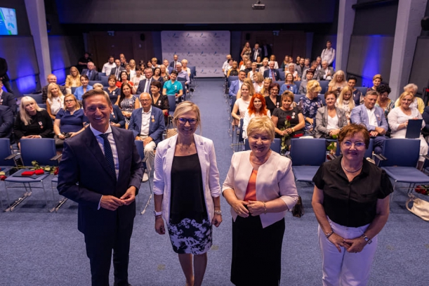 Odznaki Honorowe Gryfa Zachodniopomorskiego dla środowiska medycznego. Wszyscy uczestnicy gali wręczenia odznak na tle sali.