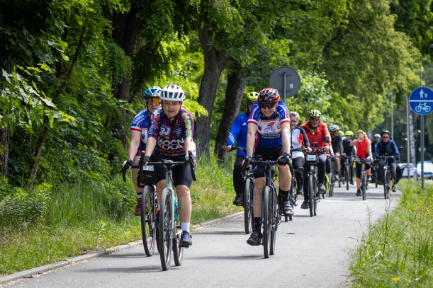 Uczestniocy jadący na rowerach, w tle tereny leśne. 
