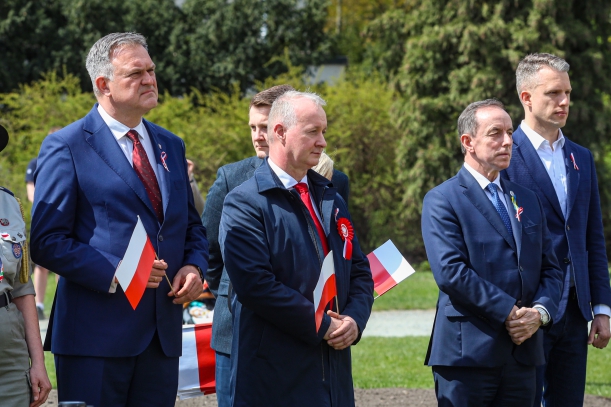 Goście przed Pomnikiem Czynu Polaków z flagami RP. 