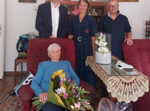 Spotkanie z okazji 100 urodzin Lidii Więckowskiej, kombatantki, żołnierki Armii Krajowej. Zdjecie wykonane w mieszkaniu jubilatki. Pani Lidia siedzi w fotelu. Obok niej stoi wicedyrektor Gabinetu Marszałka - Marcin Kordela, a także kobieta i mężczyzna.