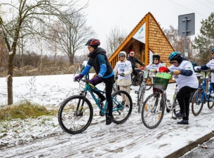 Rowerzyści na rowerach, w tle wiata. 